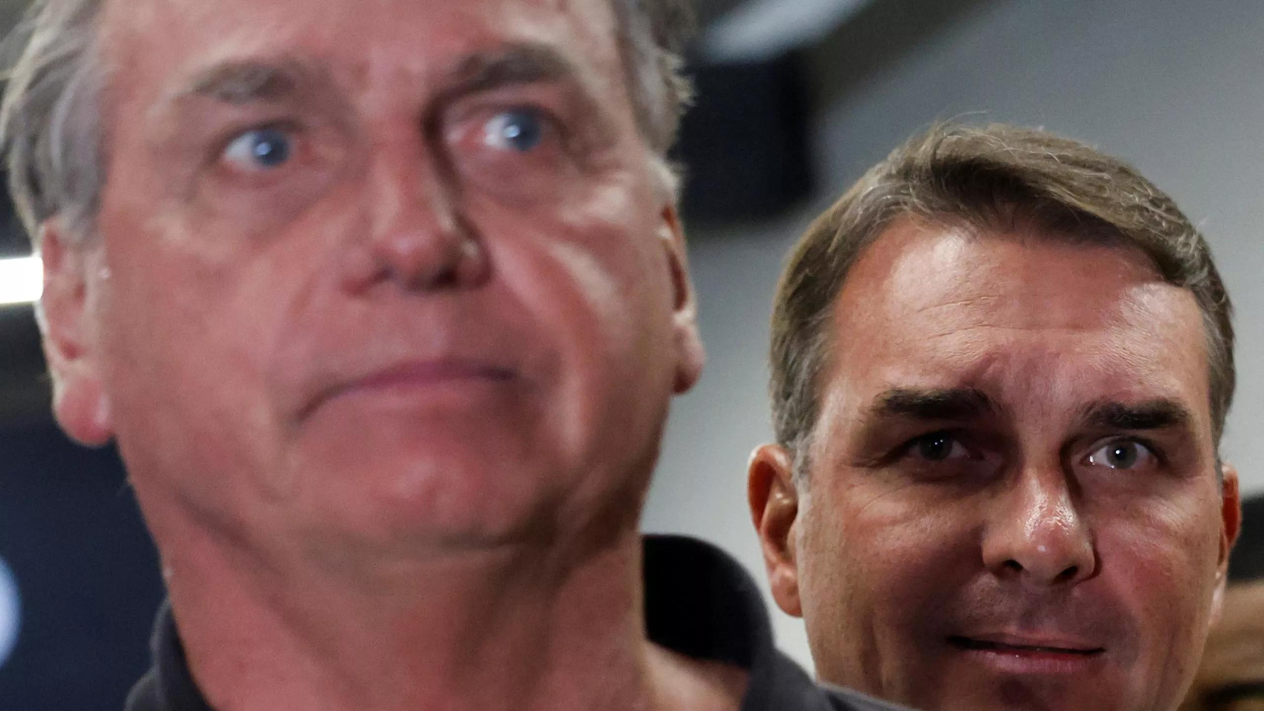 O senador Flávio Bolsonaro observa o pai, o ex-presidente Jair Bolsonaro, no Aeroporto Internacional de Brasília - 25/11/2024