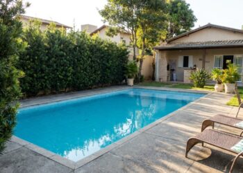 A escolha de plantas estratégicas cria uma cerca viva que garante privacidade na piscina sem espalhar sujeira.