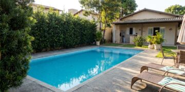 A escolha de plantas estratégicas cria uma cerca viva que garante privacidade na piscina sem espalhar sujeira.