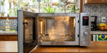 Qual a finalidade de deixar uma xícara com vinagre branco aquecido dentro do micro-ondas fechado por cinco minutos e por que isso é recomendado?