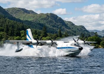 Avião anfíbio quadrimotor deslizando sobre lago e levantando spray de água ao reabastecer os tanques