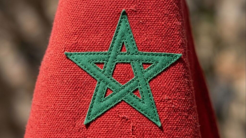Por que a bandeira do Marrocos possui uma estrela verde vazada no centro de um fundo vermelho escuro, e o que ela significa?
