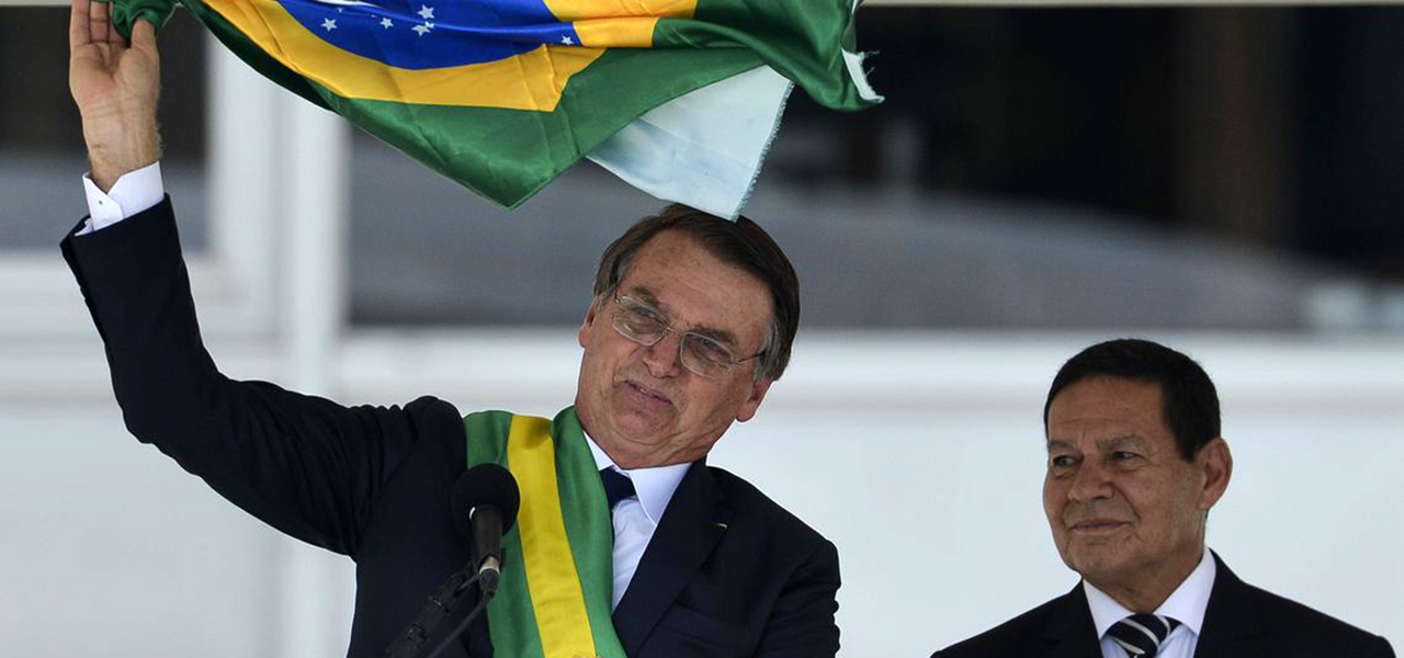 Presidente Jair Bolsonaro e o vice-presidente Hamilton Mourão exibem uma bandeira nacional durante discurso no parlatório do Palácio do Planalto.