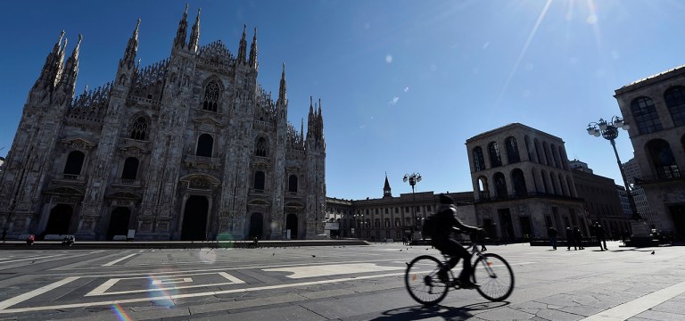 Ciclista passa em frente à catedral de Milão, com ambientes públicos desertos por conta do coronavírus