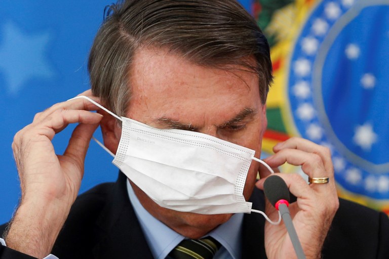 Brazil's President Jair Bolsonaro wearing a protective face masks reacts during a news conference to announce measures to curb the spread of the coronavirus disease (COVID-19) in Brasilia, Brazil March 18, 2020. REUTERS/Adriano Machado