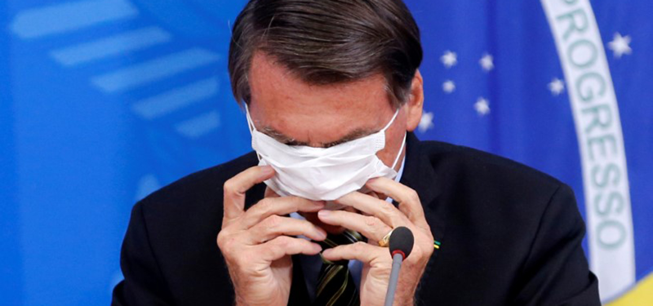 Presidente Jair Bolsonaro coloca máscara durante entrevista coletiva sobre coronavírus no Palácio do Planalto