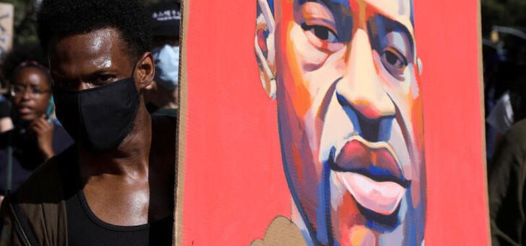 Manifestante segura cartaz com rosto de George Floyd durante protesto em Nova York