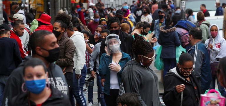 Pessoas caminham em rua de comércio popular em São Paulo
