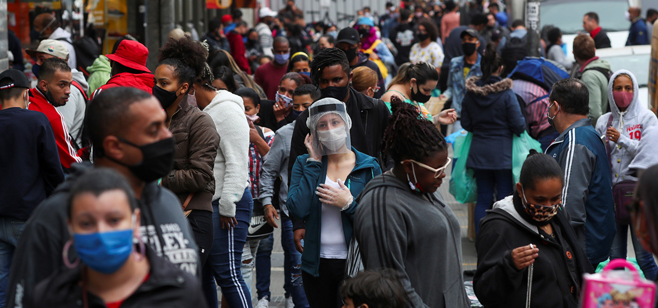 Pessoas caminham em rua de comércio popular em São Paulo