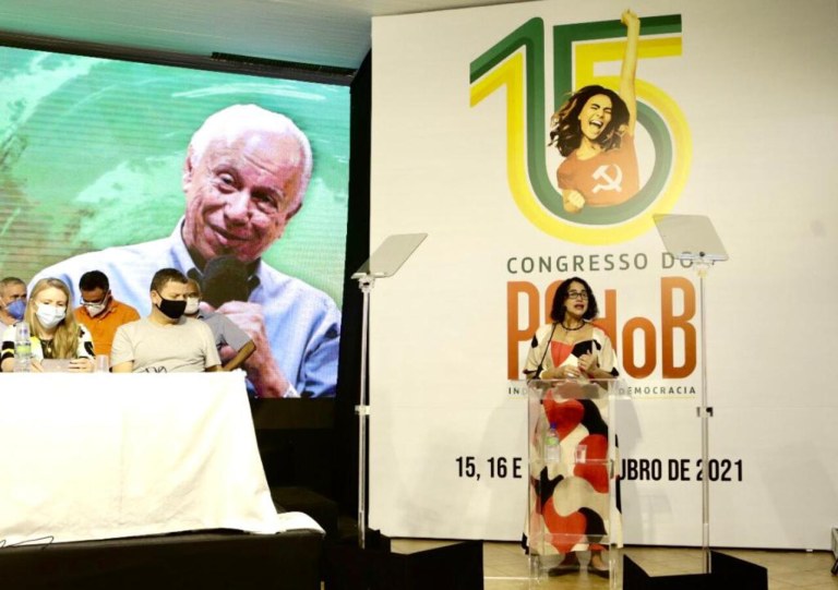 Luciana Santos, presidente do PCdoB. No painel ao fundo, imagem de Haroldo Lima, dirigente do partido falecido em março último, homenageado no congresso