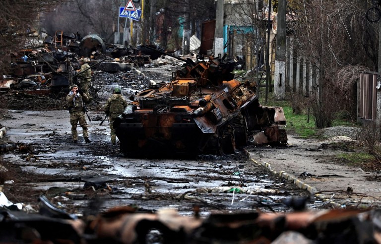 Um soldado tira uma foto de seu companheiro enquanto ele posa ao lado de um tanque russo destruído e veículos blindados, em meio à invasão da Rússia na Ucrânia em Bucha, na região de Kiev, Ucrânia 2 de abril de 2022