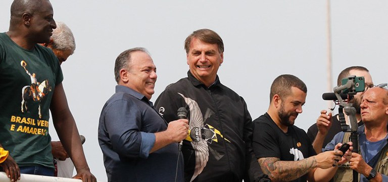 Eduardo Pazuello (com microfone na mão) e Jair Bolsonaro (agasalho preto)