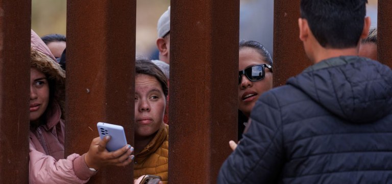 Um menino migrante espera por comida na cerca da fronteira enquanto os migrantes se reúnem entre as cercas primária e secundária da fronteira, perto de San Diego, Califórnia, 10 de maio