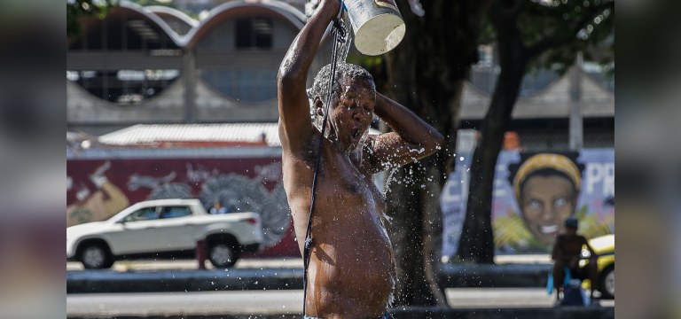 Homem toma banho na rua em meio ao calor no Rio de Janeiro