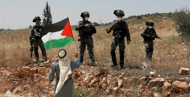 Um palestino protesta em frente a soldados israelenses