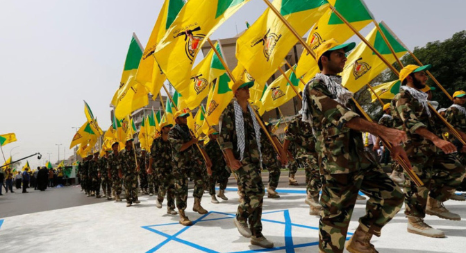 Homens muçulmanos xiitas iraquianos do Kataib Hezbollah seguram as bandeiras do partido enquanto caminham por uma rua pintada com as cores da bandeira israelense durante um desfile que marca o Dia Quds anual, ou Dia de Jerusalém, na última sexta-feira de o mês sagrado muçulmano do Ramadã, em Bagdá, 25 de julho de 2014
