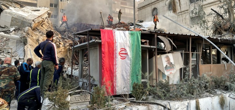 Bandeira iraniana é vista enquanto fumaça sobe após o que a mídia iraniana disse ter sido um ataque israelense a um prédio próximo à embaixada iraniana em Damasco