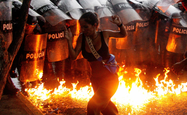 Uma manifestante reage quando coquetéis molotov atingem o chão em frente às forças de segurança durante os protestos contra os resultados das eleições, após o presidente da Venezuela, Nicolás Maduro, e seu rival da oposição, Edmundo Gonzalez, reivindicarem a vitória na eleição presidencial de domingo, em Puerto La Cruz, Venezuela