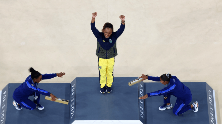 A medalhista de ouro Rebeca Andrade, do Brasil, comemora com a medalhista de prata Simone Biles, dos Estados Unidos, e a medalhista de bronze Jordan Chiles, dos Estados Unidos, no pódio