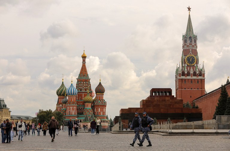 Pessoas atravessam a Praça Vermelha perto da Catedral de São Basílio e da Torre Spasskaya do Kremlin, no centro de Moscou, Rússia
