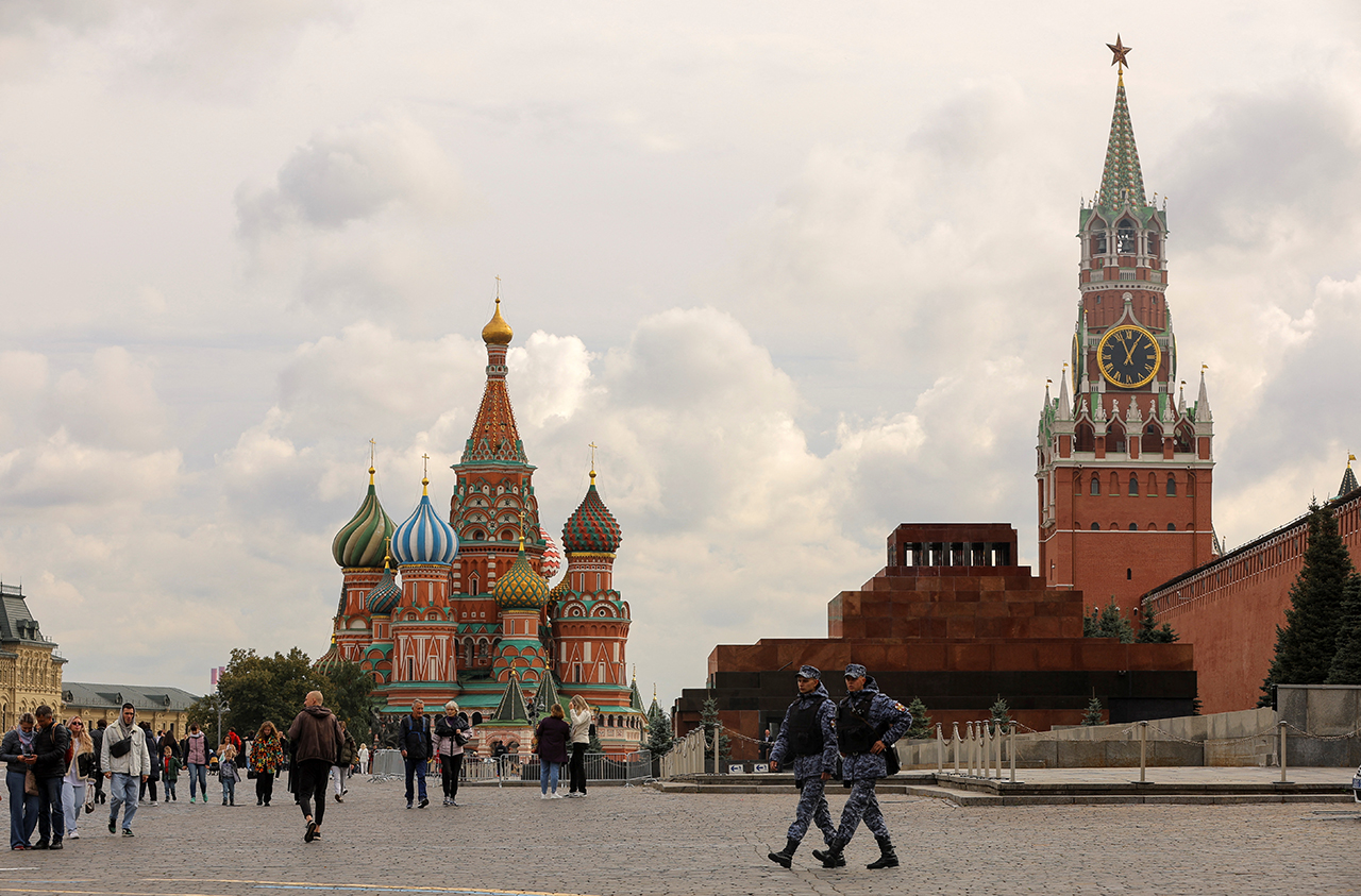 Pessoas atravessam a Praça Vermelha perto da Catedral de São Basílio e da Torre Spasskaya do Kremlin, no centro de Moscou, Rússia