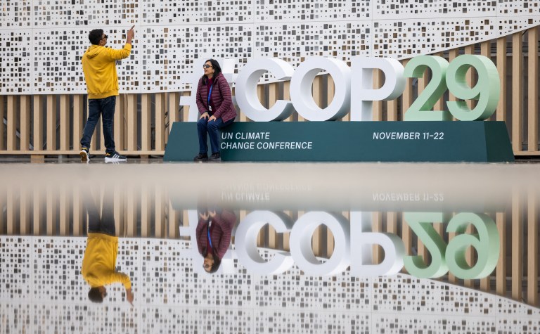 Pessoas tiram fotos na entrada do local da conferência da ONU de mudanças climáticas (COP29), antes do início da cúpula em Baku, Azerbaijão 
10/11/2024