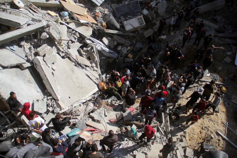 Palestinos, incluindo equipes de resgate, procuram vítimas no local de um ataque israelense a uma casa, na Cidade de Gaza