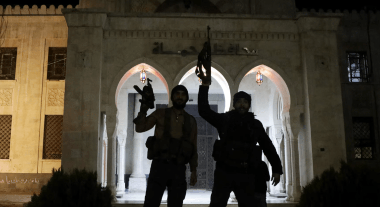 Terroristas seguram armas em frente ao prédio do governo de Hama