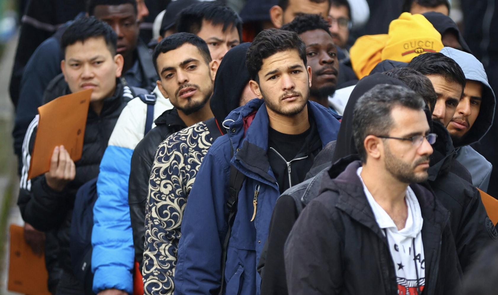 Migrantes fazem fila em uma área de espera para serem escoltados até um escritório de registro no centro de chegada para requerentes de asilo no distrito de Reinickendorf, Berlim, Alemanha, 6 de outubro de 2023