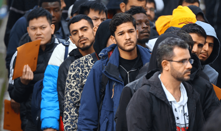 Migrantes fazem fila em uma área de espera para serem escoltados até um escritório de registro no centro de chegada para requerentes de asilo no distrito de Reinickendorf, Berlim, Alemanha, 6 de outubro de 2023