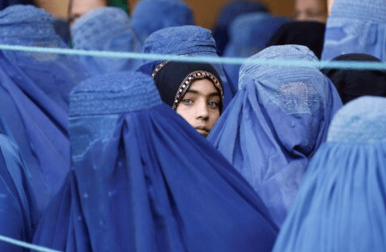 Uma menina observa entre mulheres afegãs que fazem fila para receber assistência humanitária, durante o mês sagrado do Ramadã em Jalalabad, Afeganistão, 11 de junho de 2017