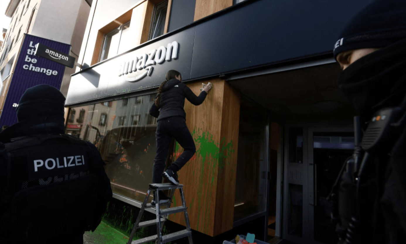 A polícia suíça fica em frente a um espaço da Amazon enquanto uma mulher limpa a vitrine depois que ativistas pintaram sua fachada com spray durante um protesto no dia de abertura da 55ª reunião anual do Fórum Econômico Mundial (WEF) em Davos, Suíça , 20 de janeiro de 2025