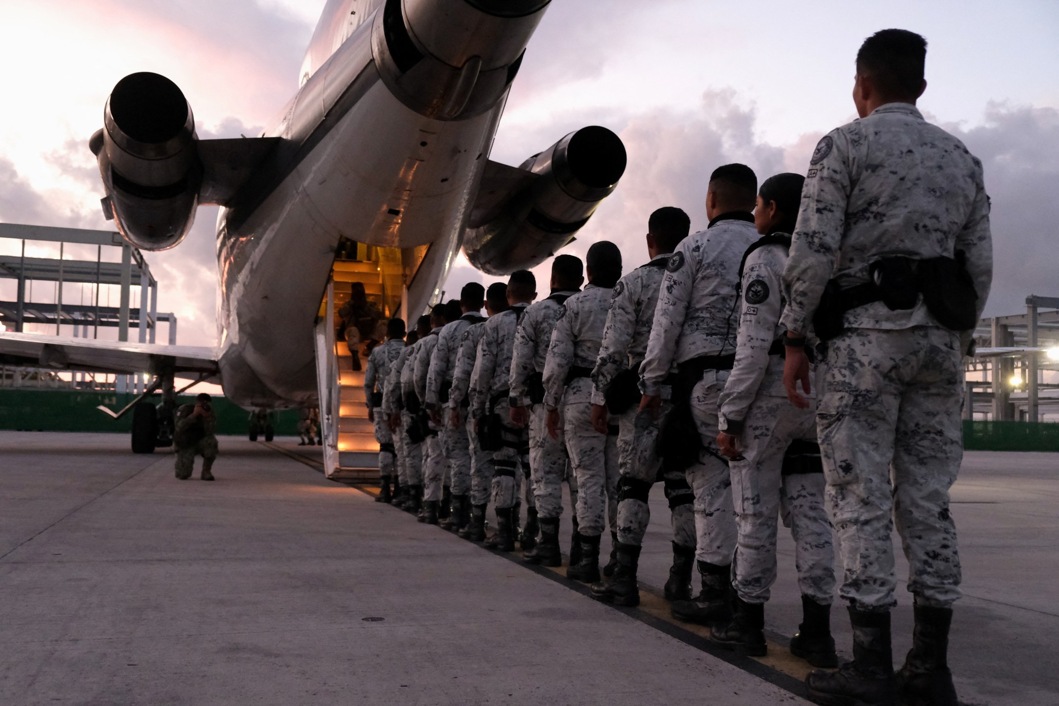 Membros da Guarda Nacional do México fazem fila para embarcar em avião com destino à fronteira norte, no Aeroporto Internacional de Cancún, México