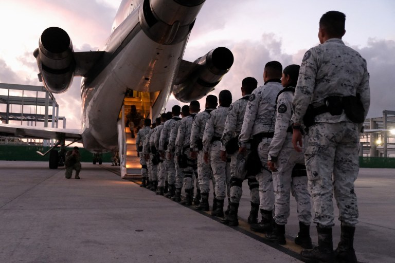 Membros da Guarda Nacional do México fazem fila para embarcar em avião com destino à fronteira norte, no Aeroporto Internacional de Cancún, México