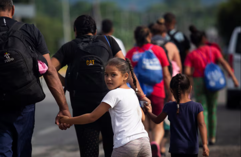 Crianças dão as mãos aos pais enquanto caminham com outros migrantes em uma caravana para cruzar o país e chegar à fronteira com os EUA, enquanto líderes regionais se reúnem em Los Angeles para discutir migração e outras questões, em Huixtla, México, em 7 de junho de 2022.
