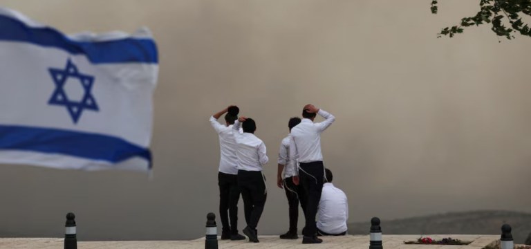 Pessoas observam a fumaça em Neve Ilan, enquanto incêndios florestais causados por calor extremo e ventos fortes irrompem no centro de Israel