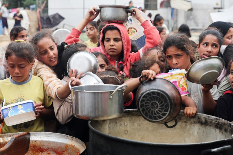 Palestinos aguardam para receber comida preparada por uma cozinha comunitária, em Nuseirat, Faixa de Gaza
08/04/2025
