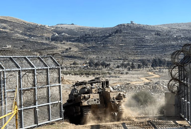 Um veículo blindado de transporte de pessoal israelense (APC) entra na Síria na linha de cessar-fogo com a Síria e as Colinas de Golã ocupadas por Israel, visto das Colinas de Golã, em 13 de dezembro de 2024
