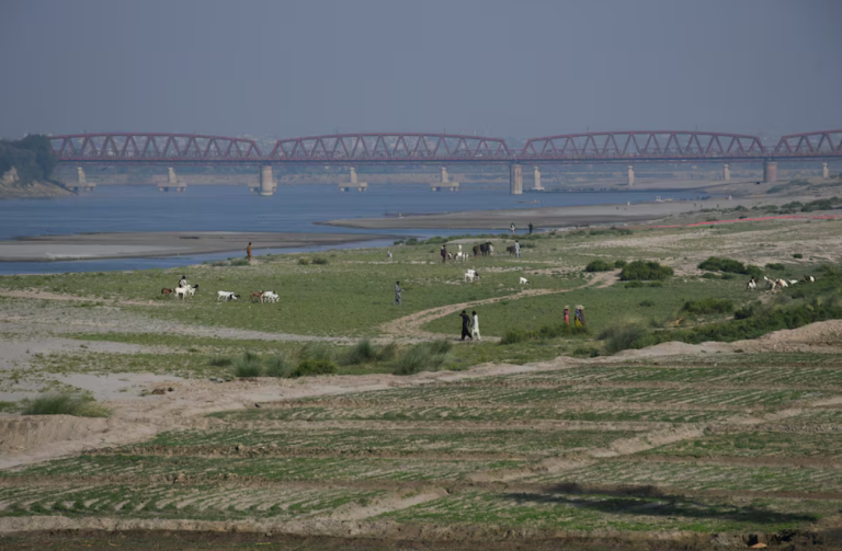 Pessoas caminham ao lado de uma terra cultivada no leito seco do rio Indo, em Hyderabad, Paquistão, em 25 de abril de 2025