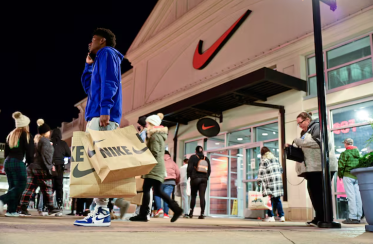 Um homem com bolsas da Nike fala ao telefone em frente a uma loja da Nike durante o início das vendas da Black Friday no The Outlet Shoppes of the Bluegrass em Simpsonville, Kentucky, EUA, em 26 de novembro de 2021