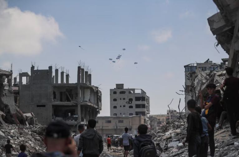 Palestinos observam pacotes de ajuda lançados de avião sobre Gaza, na Cidade de Gaza, em 8 de agosto de 2025