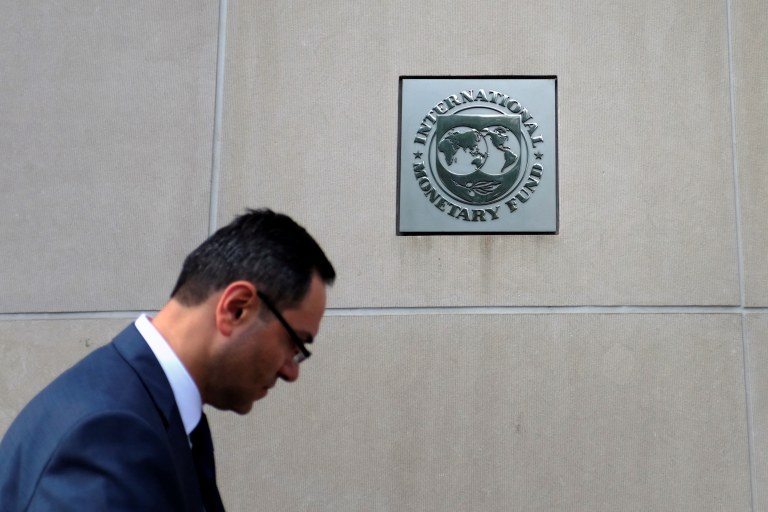 Homem caminha perto de logo do FMI na sede do Fundo, em Washington, D.C., EUA - 12/10/2022