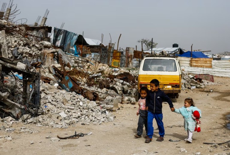 Crianças palestinas caminham entre os escombros de prédios residenciais destruídos na Cidade de Gaza, em 28 de janeiro de 2026