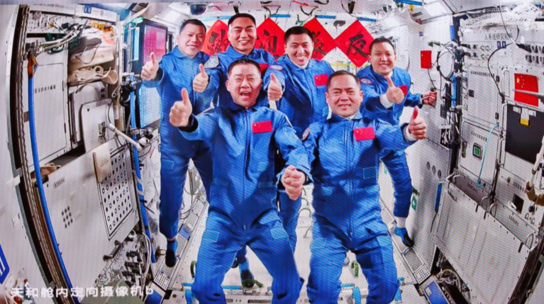Esta imagem, capturada no Centro de Controle Aeroespacial de Pequim em 1º de novembro de 2025, mostra uma foto de grupo da tripulação das naves espaciais Shenzhou-20 e Shenzhou-21, na estação espacial da China.