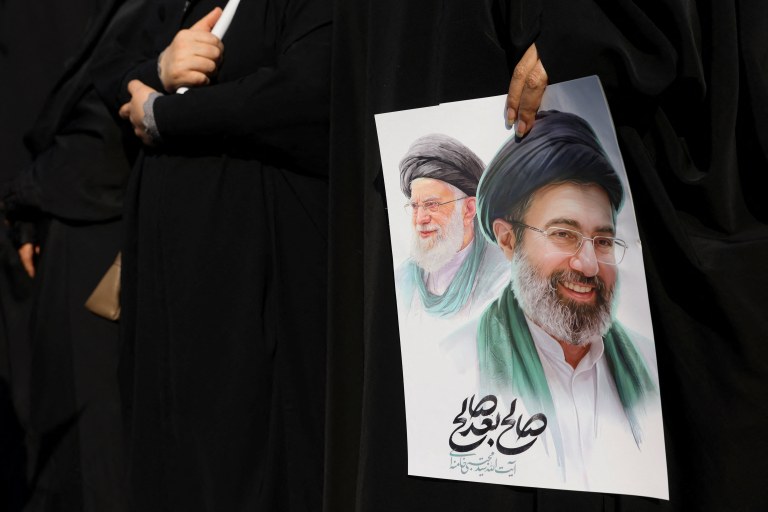 Mulher segura imagem do novo líder supremo do Irã, Mojtaba Khamenei, e do líder anterior, o aiatolá Ali Khamenei, durante cerimônia fúnebre para comandantes militares iranianos 
11 de março de 2026
Majid Asgaripour/WANA  via REUTERS