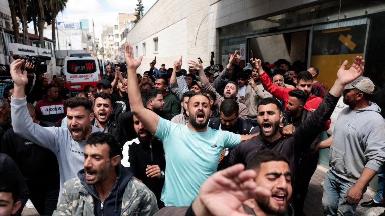 Pessoas reagem enquanto os corpos de dois palestinos, mortos durante um ataque de colonos israelenses, são transportados em um hospital em Ramallah, na Cisjordânia ocupada por Israel, em 21 de abril de 2026