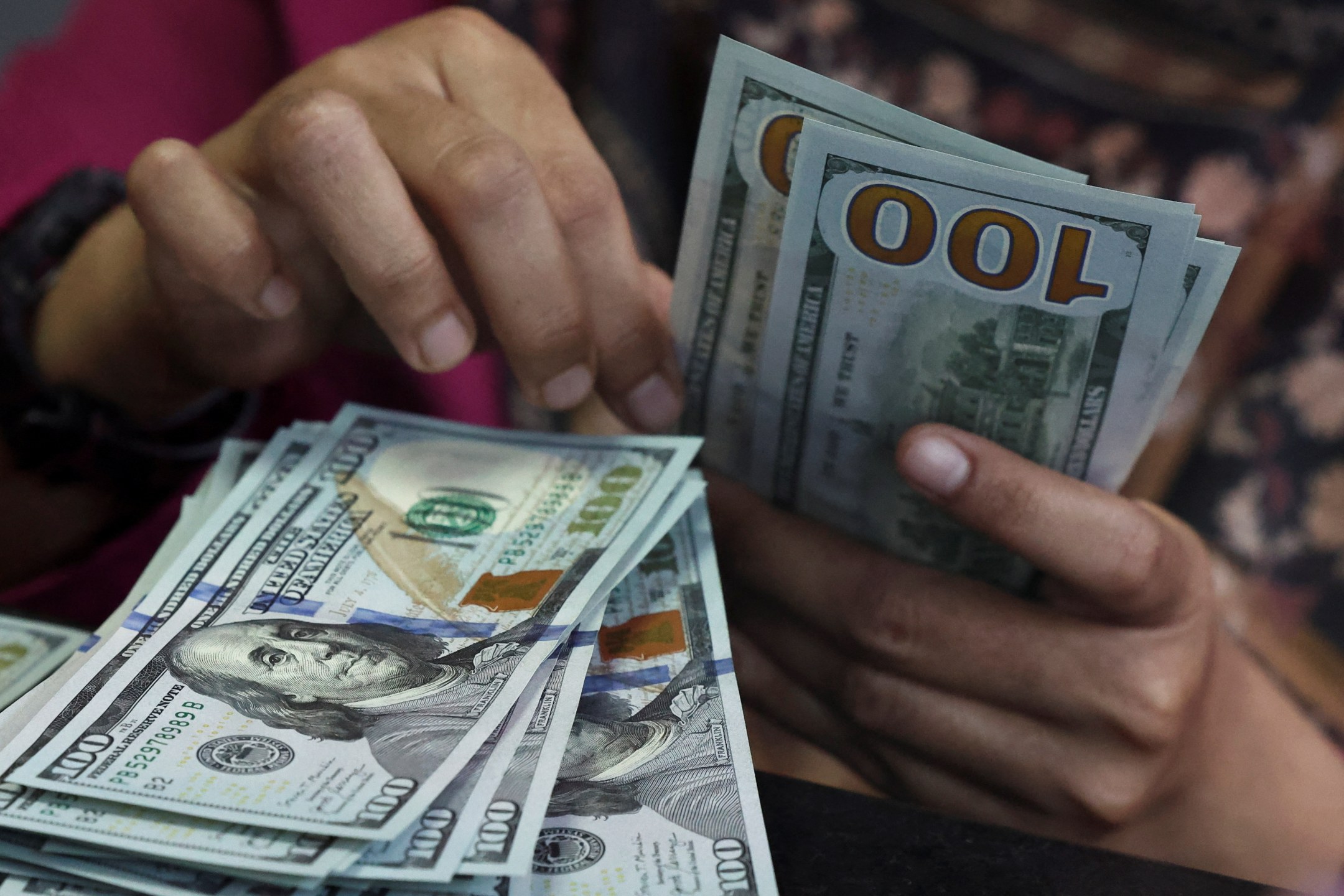 Pessoa conta notas de dólar em uma casa de câmbio em Jacarta, Indonésia, em 9 de abril de 2025.