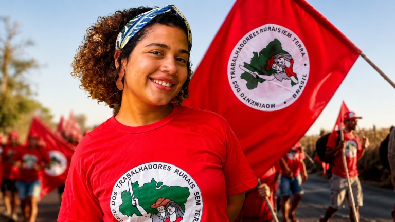 Parlamentar Maíra do MST e uma bandeira com integrantes do movimento
