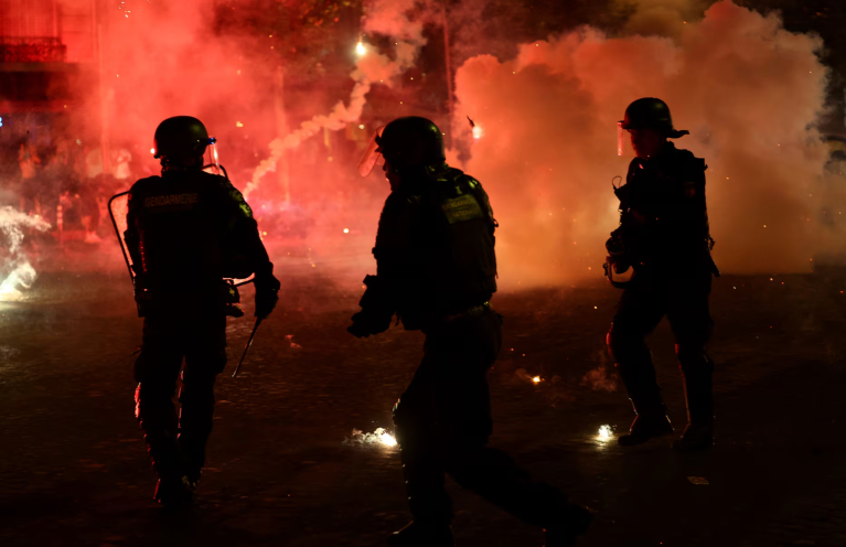 Policiais se protegem de sinalizadores após o Paris Saint-Germain vencer a Liga dos Campeões da UEFA