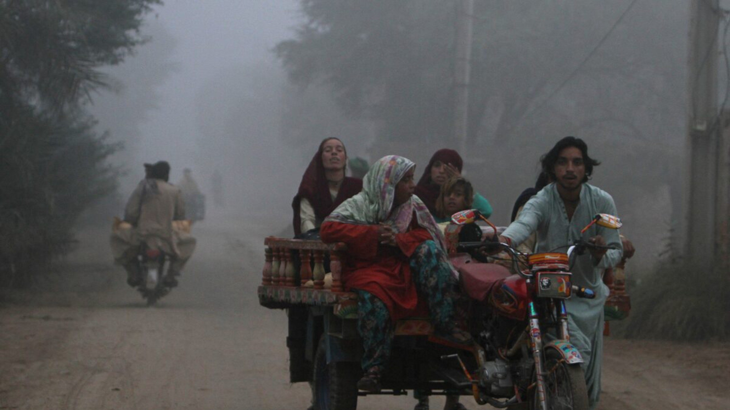 Uma família se desloca em um triciclo motorizado por uma estrada em uma manhã com forte neblina de poluição (smog) nos arredores de Multan, no Paquistão
